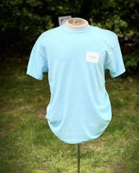 a light blue t - shirt on a mannequin in the grass