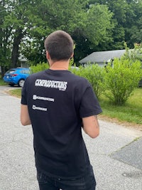 a man in a black t - shirt standing on a street