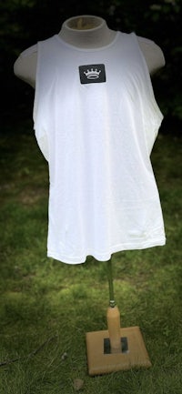 a white tank top on a wooden mannequin in the grass