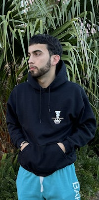 a man wearing a black hoodie and blue sweatpants