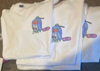 two white t - shirts with cartoon characters on them