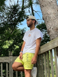 a man in yellow shorts leaning against a fence